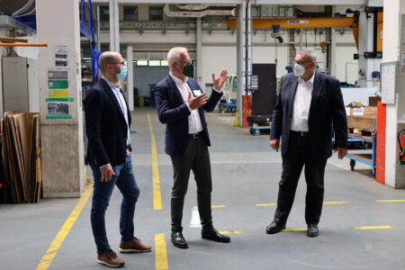 Thomas Zawalski in einer Werkhalle im Gespräch mit den Geschäftsführern Holger Wössner und Uwe Meißner.